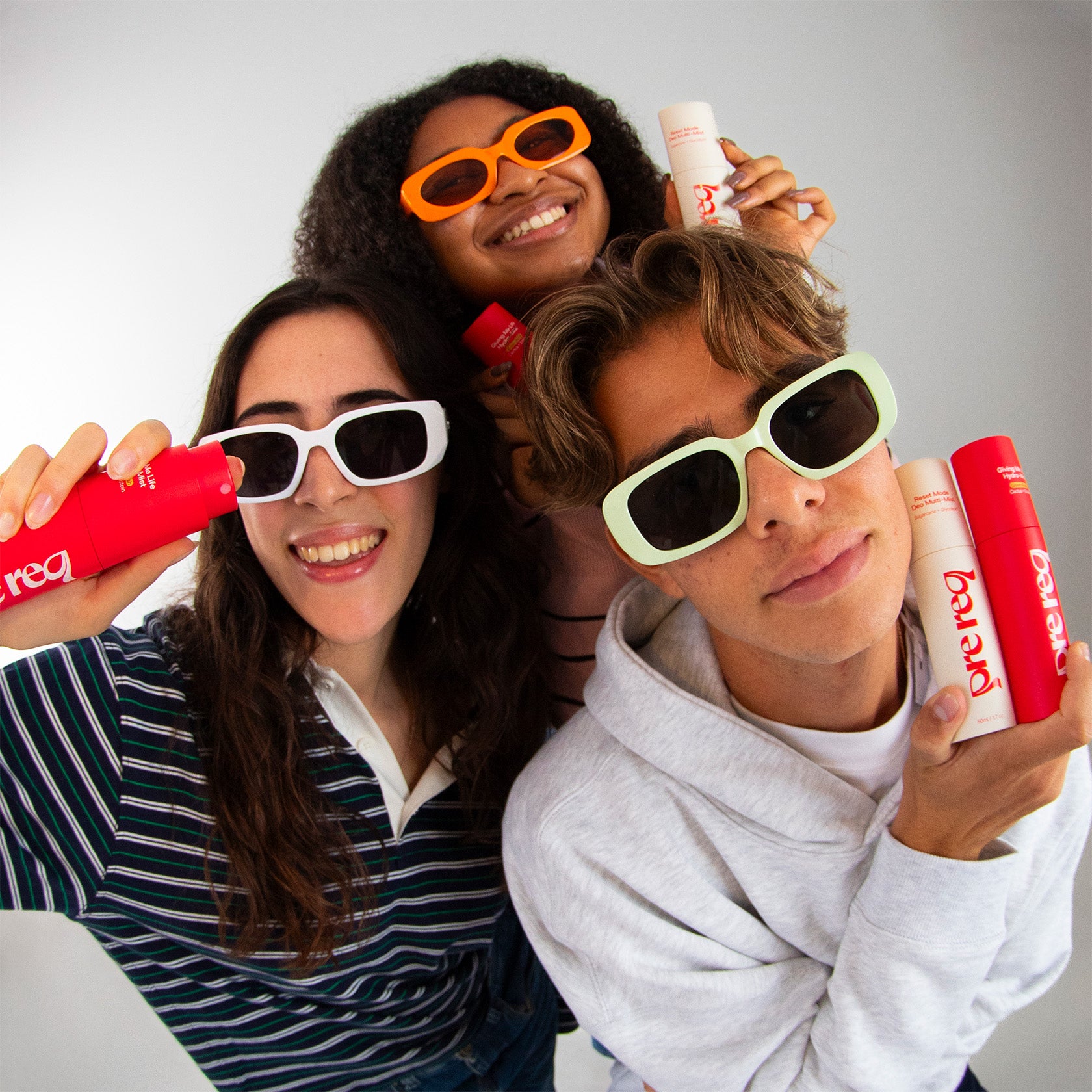 Three people wearing colorful sunglasses and holding prereq deo against a white background
