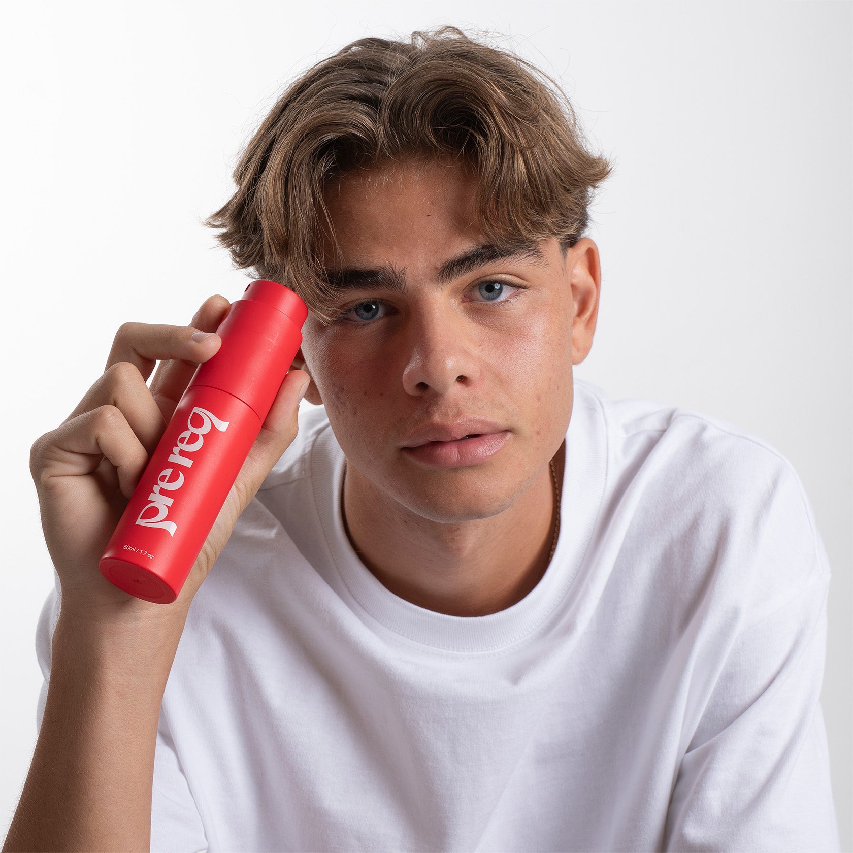 Person holding a red can of Prereq with a plain background