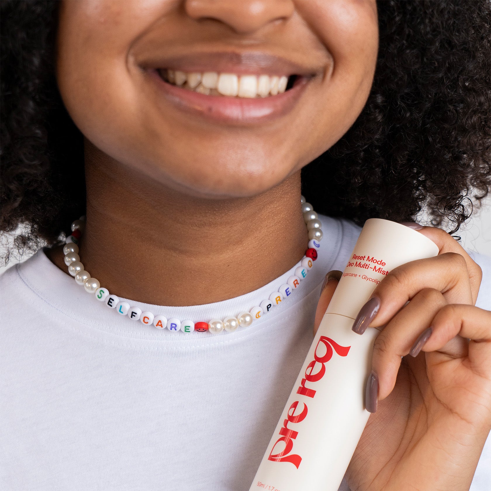 Person holding a bottle of Prereq with a colorful beaded necklace