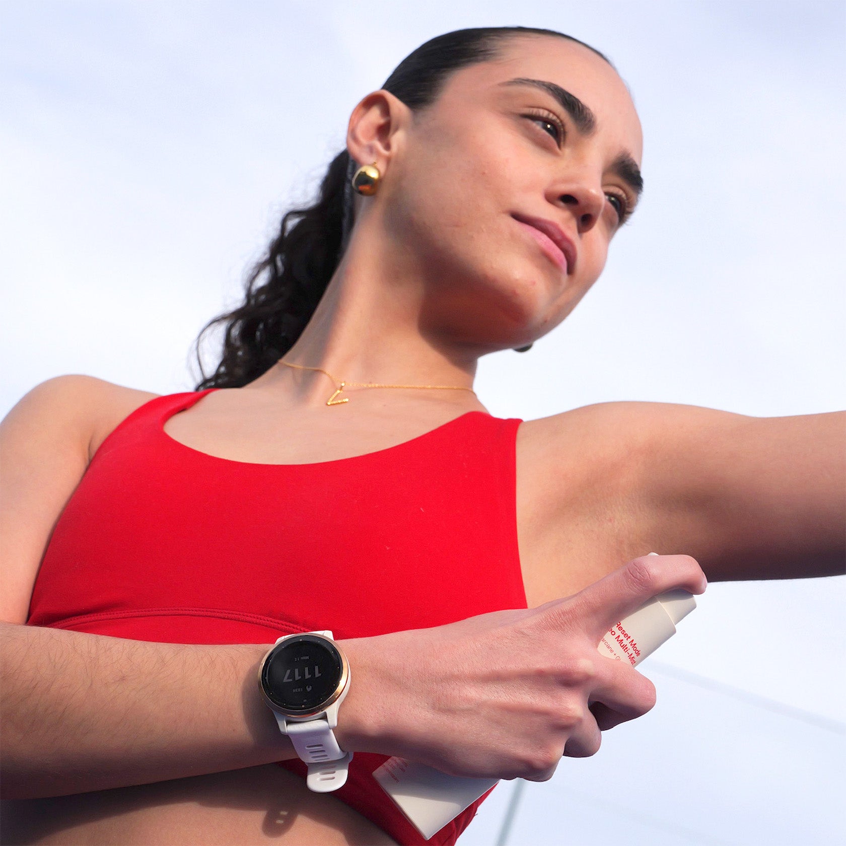 Woman in a red top spraying prereq deo with a white background