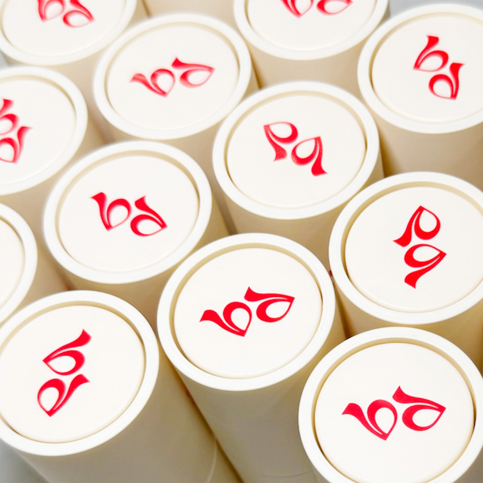 White cylindrical containers with red symbols of Prereq best deodorant brand on a beige background