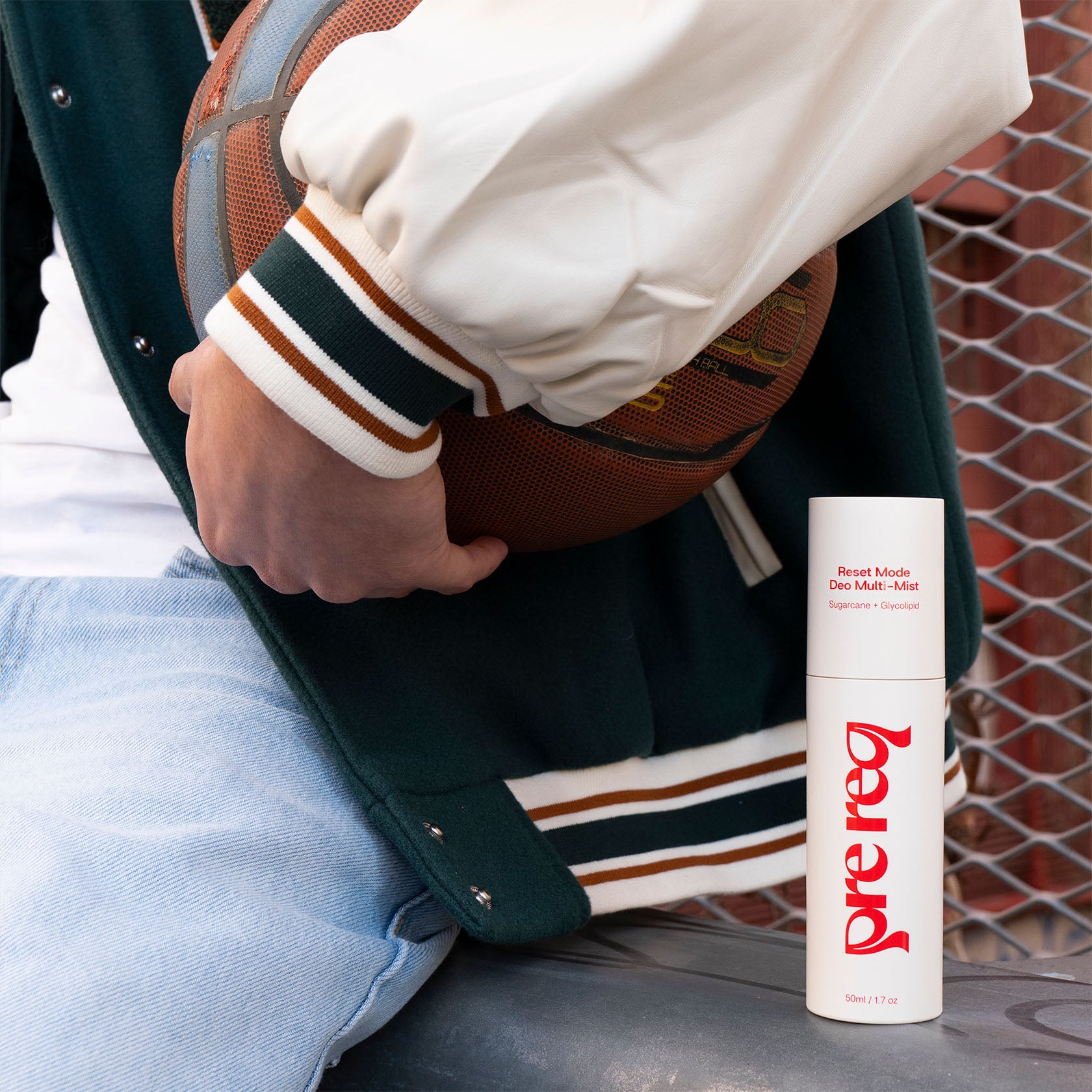 Person holding a basketball with a bottle of prereq product on the ground.