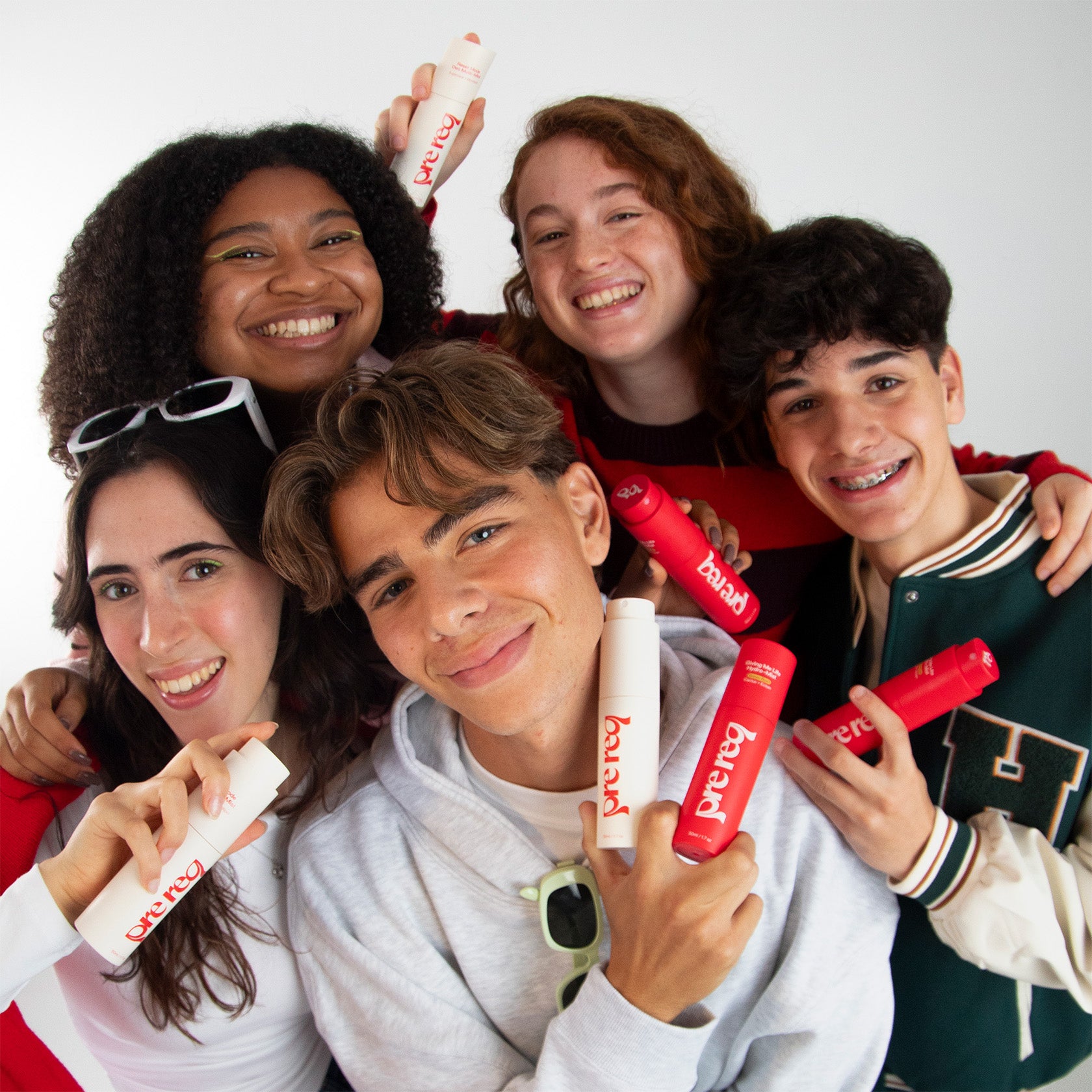 Group of five people holding red and white products against a white background